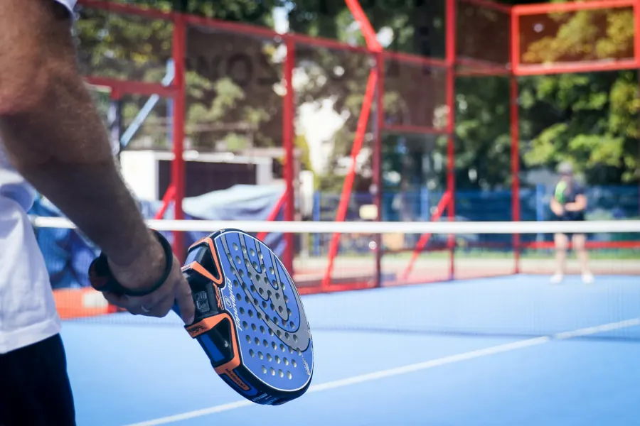 Player holding a padel racket on a blue court